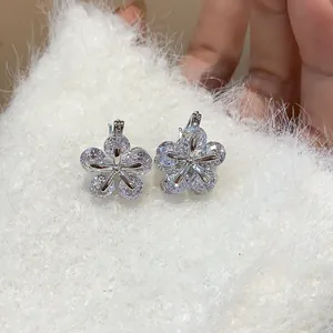 Exquisite close-up of sparkling cubic zirconia flower earrings on soft white knit background