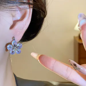 Detailed close-up view of a sparkling purple zircon flower earring worn on an earlobe