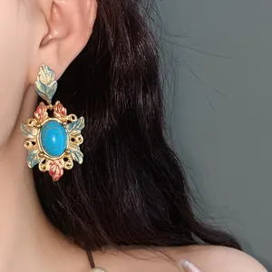 Dettaglio macro di orecchini vintage con fiori in smalto e turchese su modella