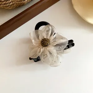 Vue détaillée d'une pince à cheveux fleur en maille beige avec centre en strass