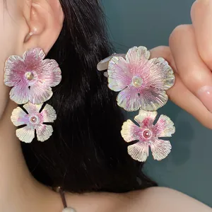 Dettaglio di orecchini a lobo vintage a forma di fiore in smalto rosa e viola iridato