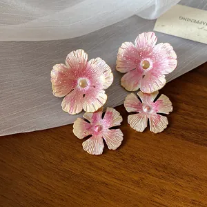 Primo piano di eleganti orecchini a lobo a fiore in smalto rosa e oro su un tavolo