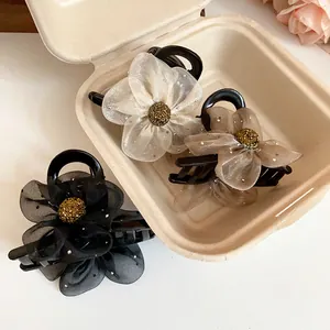 Gros plan de pinces à cheveux élégantes en tulle fleuri de couleurs blanc, brun et noir.
