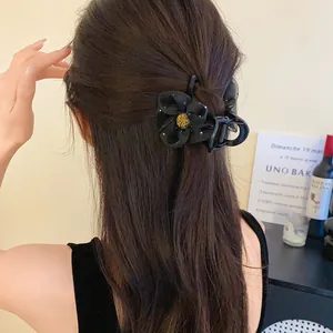 Vue détaillée d'une pince à cheveux fleur noire en résille portée par une femme