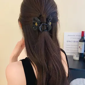 Vue détaillée arrière d'une pince à cheveux fleur en maille noire sur cheveux longs