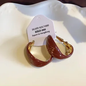 Nahaufnahme von gedrehten Retro-U-Ohrringen mit dunkelbraunem Emaille-Finish