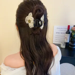 Détail de la pince à cheveux fleur en résille style français sur cheveux bruns