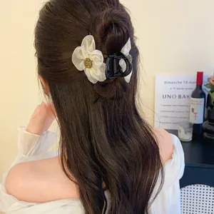 Gros plan d'une élégante pince à cheveux avec fleur en résille sur cheveux ondulés.