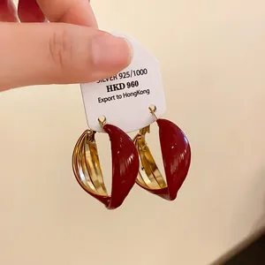Detaillierte Nahaufnahme von gedrehten U-förmigen Creolen mit rotem Emaille und Gold-Finish