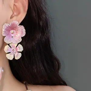 Primo piano di orecchini vintage in smalto rosa a doppio fiore indossati da una modella