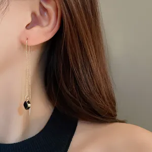 Elegante lange Quasten-Ohrfädler mit geometrischem schwarzem Anhänger am Modell-Ohr