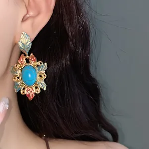Dettaglio di un orecchino vintage stile corte con pietra turchese e foglie smaltate.