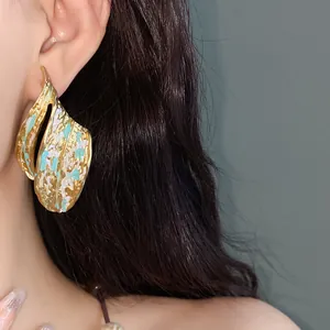 Primo piano di orecchini vintage in smalto dorato con dettagli turchesi su modella