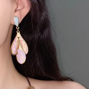 Dettaglio di orecchini vintage a fiore in smalto con tocchi rosa su base dorata lucida