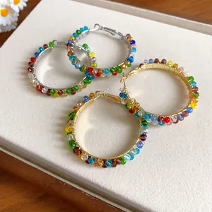 Close-up view of handmade hoop earrings wrapped with vibrant colorful faceted crystal beads.