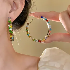 Detailed view of colorful crystal beaded hoop earrings worn on ear and held in hand