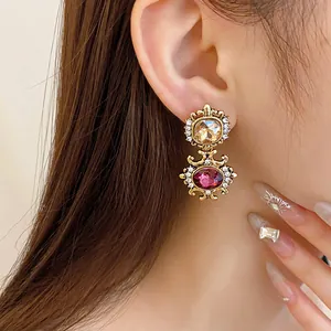 Detailed macro view of a vintage palace style gold earring with amber and pink gemstones.