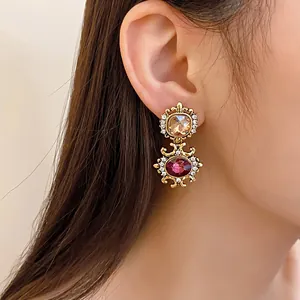Close-up of vintage palace style gold drop earrings with crystals and colored gemstones