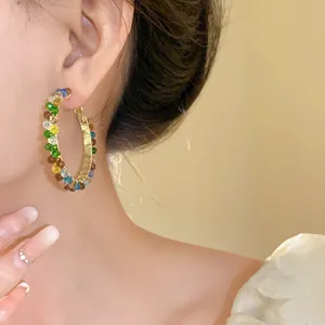 Close-up detail of elegant multi-colored crystal hoop earring worn by a model for fashion