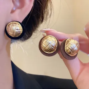 Close-up of vintage gold pleated earrings with elegant flocked fabric borders.