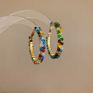 Close-up macro detail showing multi-colored faceted crystal beads on golden hoop earrings