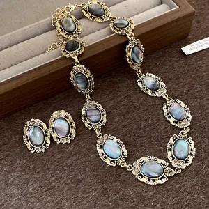 Detail view of vintage oval resin necklace and earrings with iridescent grey cabochons.