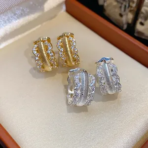 Close-up of vintage hollowed-out earrings in gold and silver plating with cubic zirconia.