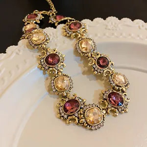 Vintage gold palace style necklace with purple and amber gemstones on white plate.