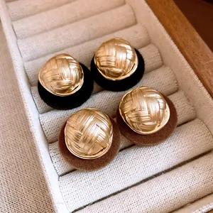 Close-up detail of vintage round earrings with gold woven texture and soft flocked base