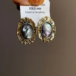 Detailed view of vintage gold-tone oval earrings with dark iridescent resin center.