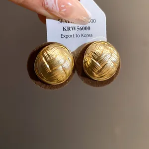 Macro view of vintage gold round earrings with pleated woven texture and flocked base