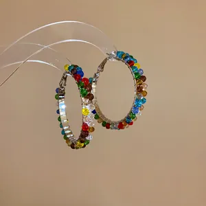 Close-up detail showing colorful crystal beads wrapped around large silver hoop earrings