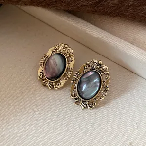 Close-up of vintage oval resin earrings with ornate gold-tone frames on textured background
