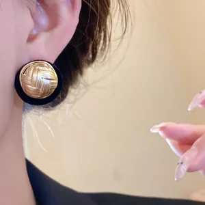 Detailed view of vintage round gold earrings with pleated texture and black flocking