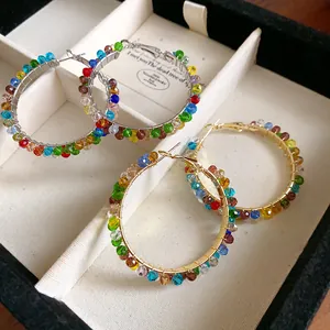 Close-up of colorful crystal beaded hoop earrings in gold and silver finishes