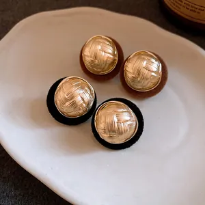 Macro view of vintage gold woven metal stud earrings with elegant flocked backing