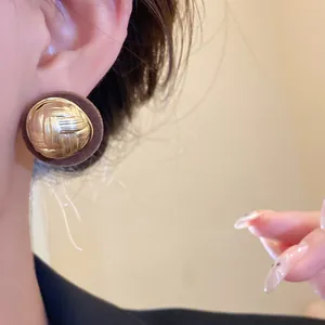 Detailed view of retro round earrings with textured gold center and brown flocked border