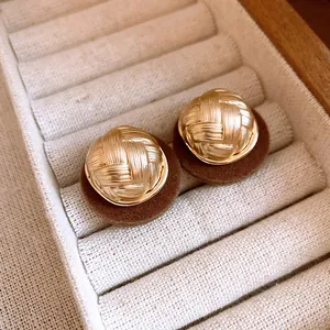 Detail of vintage gold earrings with pleated texture and brown flocked base in jewelry tray