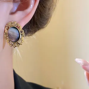 Detail view of a vintage oval gold-tone earring featuring an iridescent resin stone.