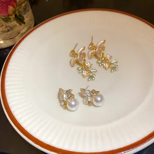 Dettaglio delle eleganti orecchini in argento con fiori e perle a forma di farfalla