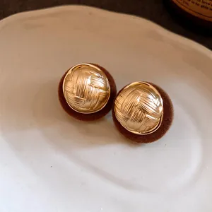 Close-up detail showing the gold woven texture and brown flocked border of retro earrings