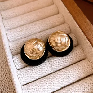 Close-up of gold woven texture earrings with black flocking base in jewelry box