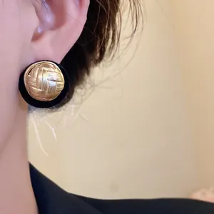 Elegant vintage circular stud earrings with woven gold texture and black velvet