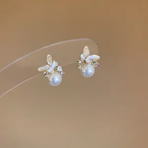 Dettaglio ravvicinato di orecchini a farfalla dorata con perla e zirconi brillanti