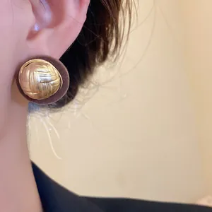 Close-up of retro round flocked stud earring with gold woven texture detail.