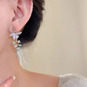 Dettaglio di orecchini a forma di ramo fiorito con fiori in smalto e cristalli