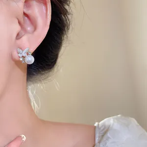 Primo piano di un elegante orecchino in argento con farfalla, perla e cristalli sull'orecchio