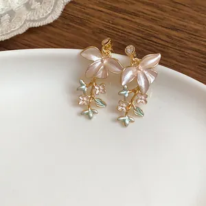 Dettaglio ravvicinato di eleganti orecchini a perno con fiori e rami in smalto rosa