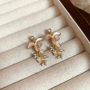 Dettaglio di orecchini eleganti a forma di fiore e ramo con smalto rosa e verde