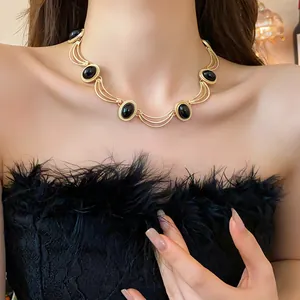 Vue détaillée d'un collier vintage avec des arcs dorés et des pierres noires ovales sur modèle.